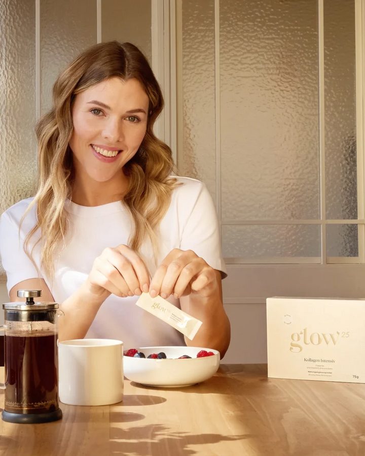 Frau am Frühstückstisch rührt Glow25 Kollagen Intensiv in ihr Getränk